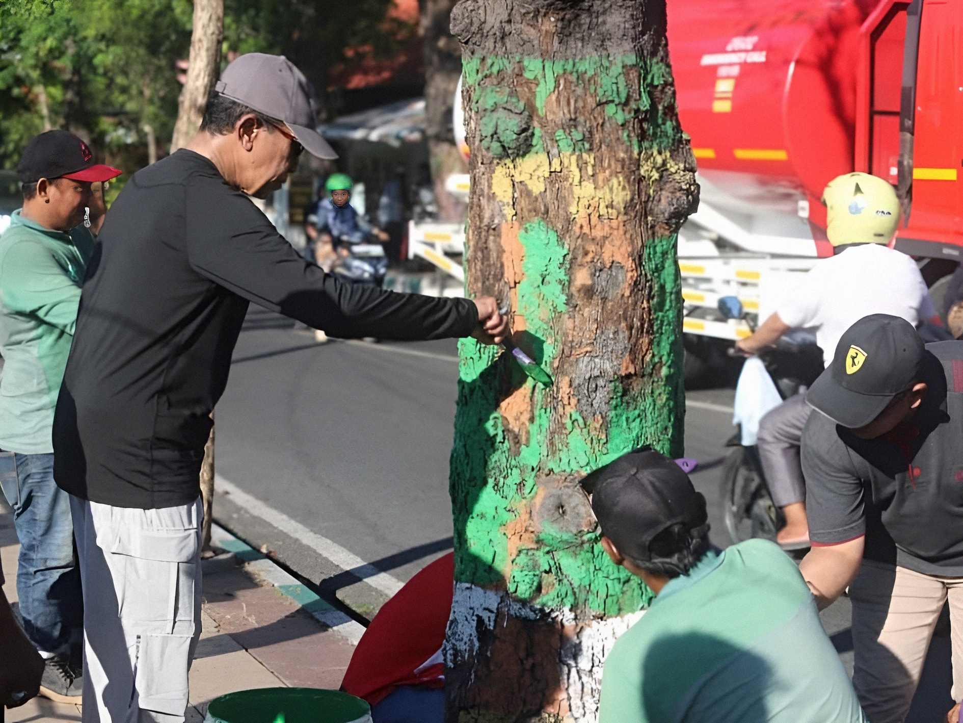 Bupati Pamekasan bersama pegawai OPD melakukan kerja bakti dan mengecat pohon di tepi jalan dalam program Pamekasan Bersih.