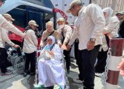 Petugas haji membantu jemaah lansia Indonesia turun dari bus menggunakan kursi roda setibanya di Makkah.