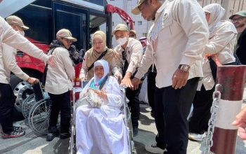 Petugas haji membantu jemaah lansia Indonesia turun dari bus menggunakan kursi roda setibanya di Makkah.