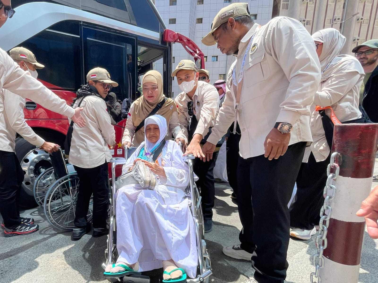 Petugas haji membantu jemaah lansia Indonesia turun dari bus menggunakan kursi roda setibanya di Makkah.