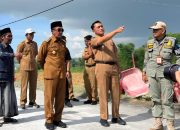 Bupati Pamekasan Kholilurrahman bersama pejabat daerah meninjau pembangunan jalan desa sambil berdiskusi di lokasi proyek.