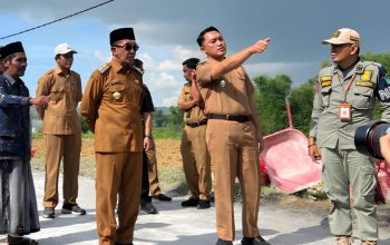 Bupati Pamekasan Kholilurrahman bersama pejabat daerah meninjau pembangunan jalan desa sambil berdiskusi di lokasi proyek.