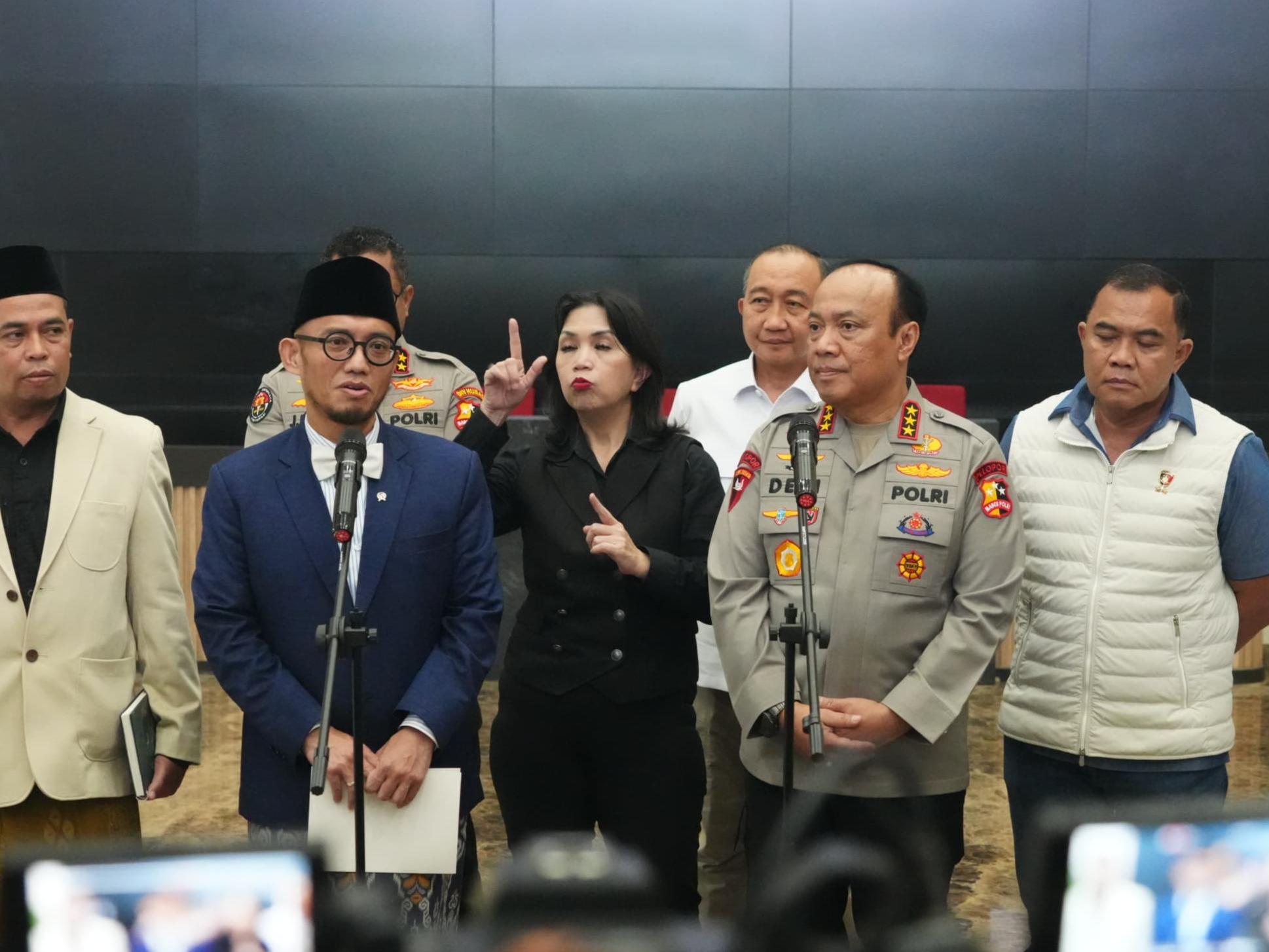 Pejabat pemerintah dan kepolisian Indonesia memberikan pernyataan pers terkait penanganan haji ilegal dengan penerjemah bahasa isyarat di tengah.