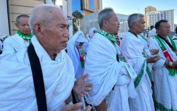 Jemaah haji Indonesia mengenakan kain ihram berdoa bersama di area sekitar Masjidil Haram, Makkah.
