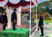 Bupati Pamekasan memimpin upacara Hardiknas 2026 di podium dengan peserta mengenakan pakaian adat di halaman kantor bupati.