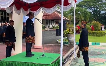 Bupati Pamekasan memimpin upacara Hardiknas 2026 di podium dengan peserta mengenakan pakaian adat di halaman kantor bupati.