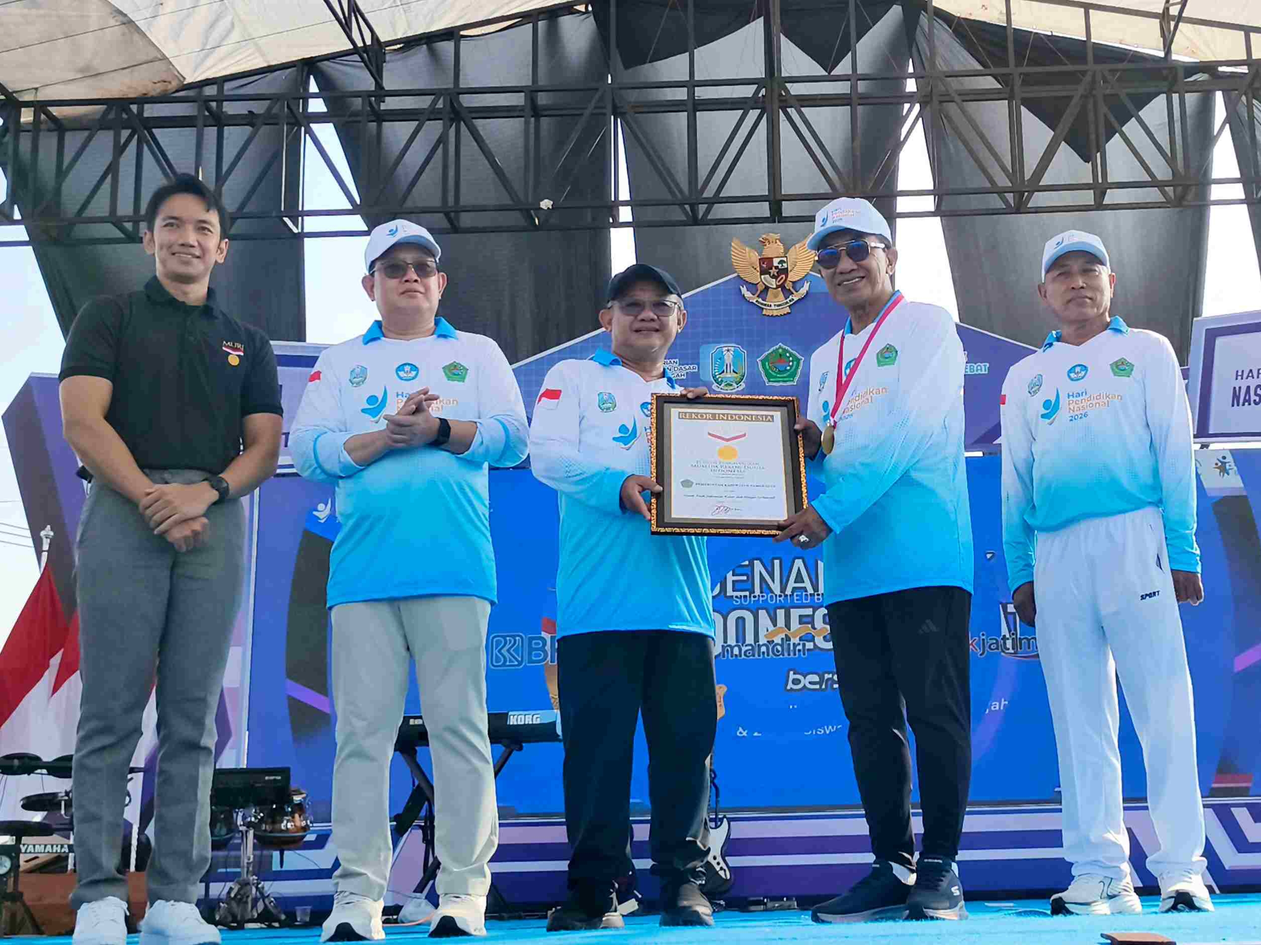Mendikdasmen Abdul Mu’ti menyerahkan piagam Rekor MURI kepada Bupati Pamekasan di panggung peringatan Hardiknas 2026.