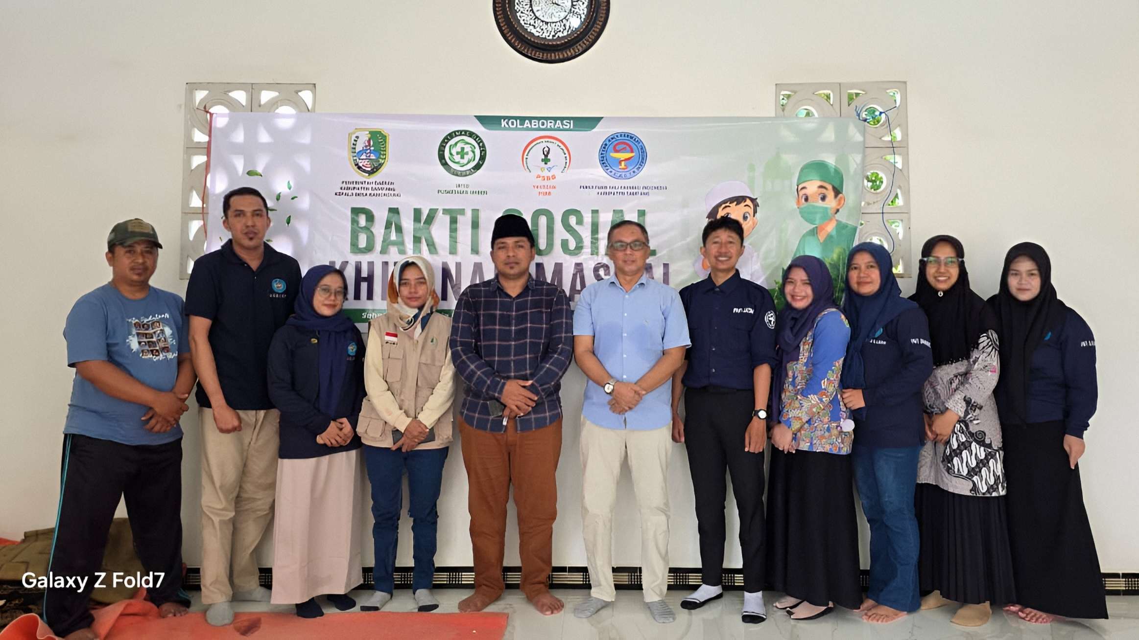 Sekelompok perwakilan instansi berfoto bersama di depan spanduk kegiatan Bakti Sosial Khitanan Massal kolaborasi empat lembaga.