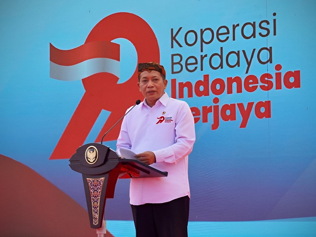 Menteri Koperasi Ferry Juliantono memberikan sambutan pada Puncak Hari Koperasi Jawa Timur 2026 di Pamekasan dengan latar logo Hari Koperasi bertuliskan "Koperasi Berdaya Indonesia Berjaya".