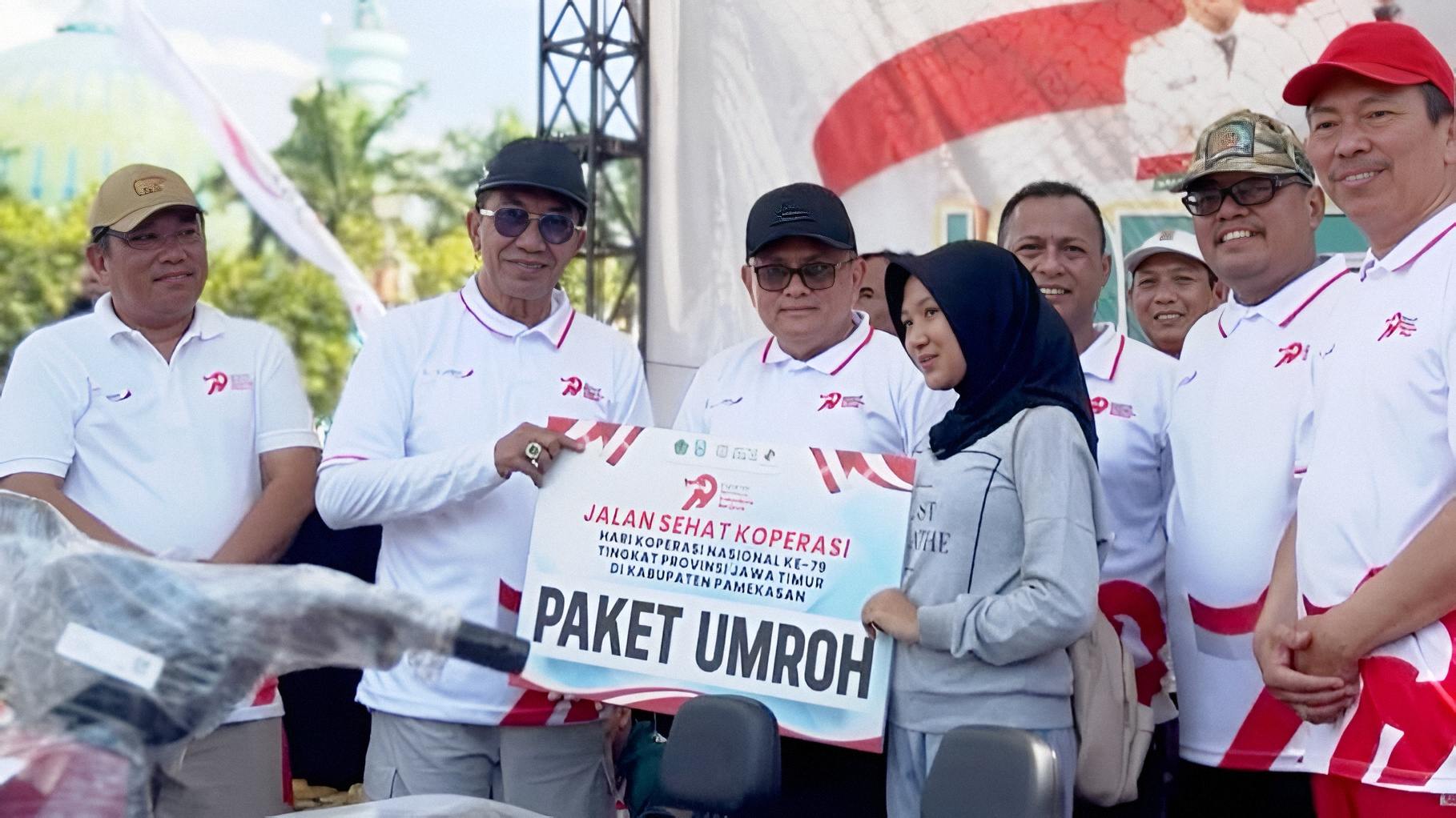 Sekda Jatim Adhy Karyono bersama Bupati Pamekasan KH Kholilurrahman menyerahkan hadiah paket umrah kepada pemenang Jalan Sehat Koperasi Harkopnas ke-79 Jawa Timur.