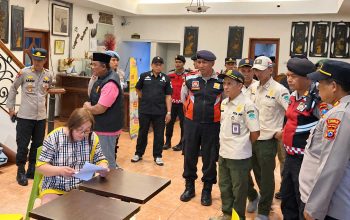 Petugas gabungan memeriksa sebuah ruangan bersama perempuan yang sedang membaca dokumen.