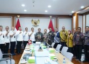 Perwakilan Pemkab Bangkalan berfoto bersama di ruang rapat dengan latar bendera Indonesia dan lambang Garuda.