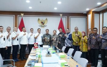 Perwakilan Pemkab Bangkalan berfoto bersama di ruang rapat dengan latar bendera Indonesia dan lambang Garuda.