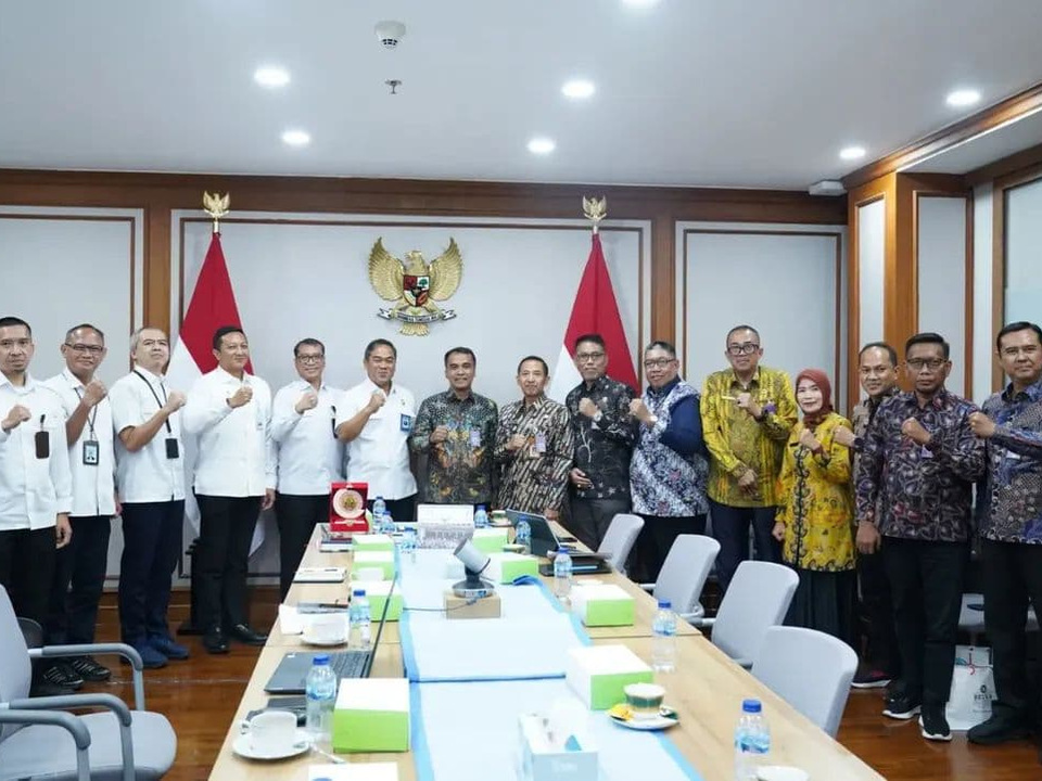 Perwakilan Pemkab Bangkalan berfoto bersama di ruang rapat dengan latar bendera Indonesia dan lambang Garuda.