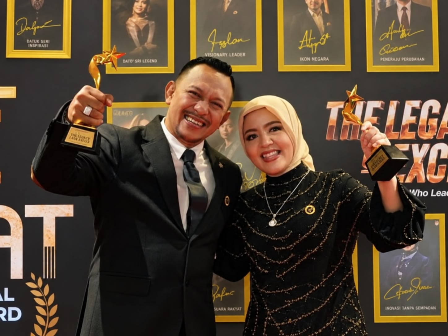 ​Bang Ali Zainal Abidin dan Fitriah Aly berhijab tersenyum bahagia sambil merayakan keberhasilan dan mengangkat piala emas pada acara penganugerahan Star Iconic Grand Honors 2026.
