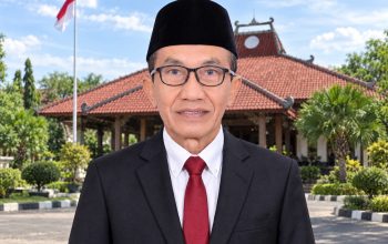 Bupati Pamekasan Kholilurrahman mengenakan jas dan peci dengan latar Pendopo Ronggosukowati.