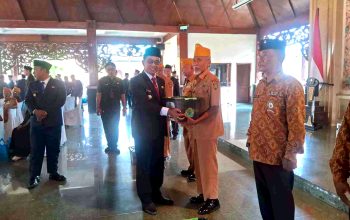 Bupati Pamekasan menyerahkan tali asih kepada veteran berseragam cokelat di Pendopo Ronggosukowati.
