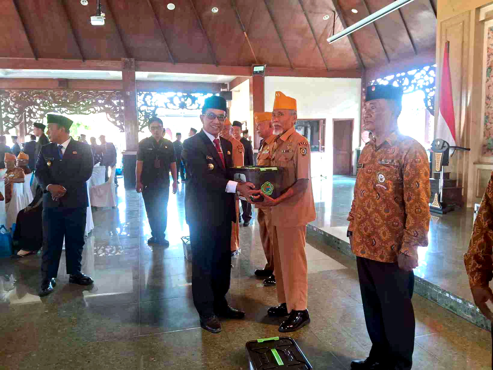 Bupati Pamekasan menyerahkan tali asih kepada veteran berseragam cokelat di Pendopo Ronggosukowati.