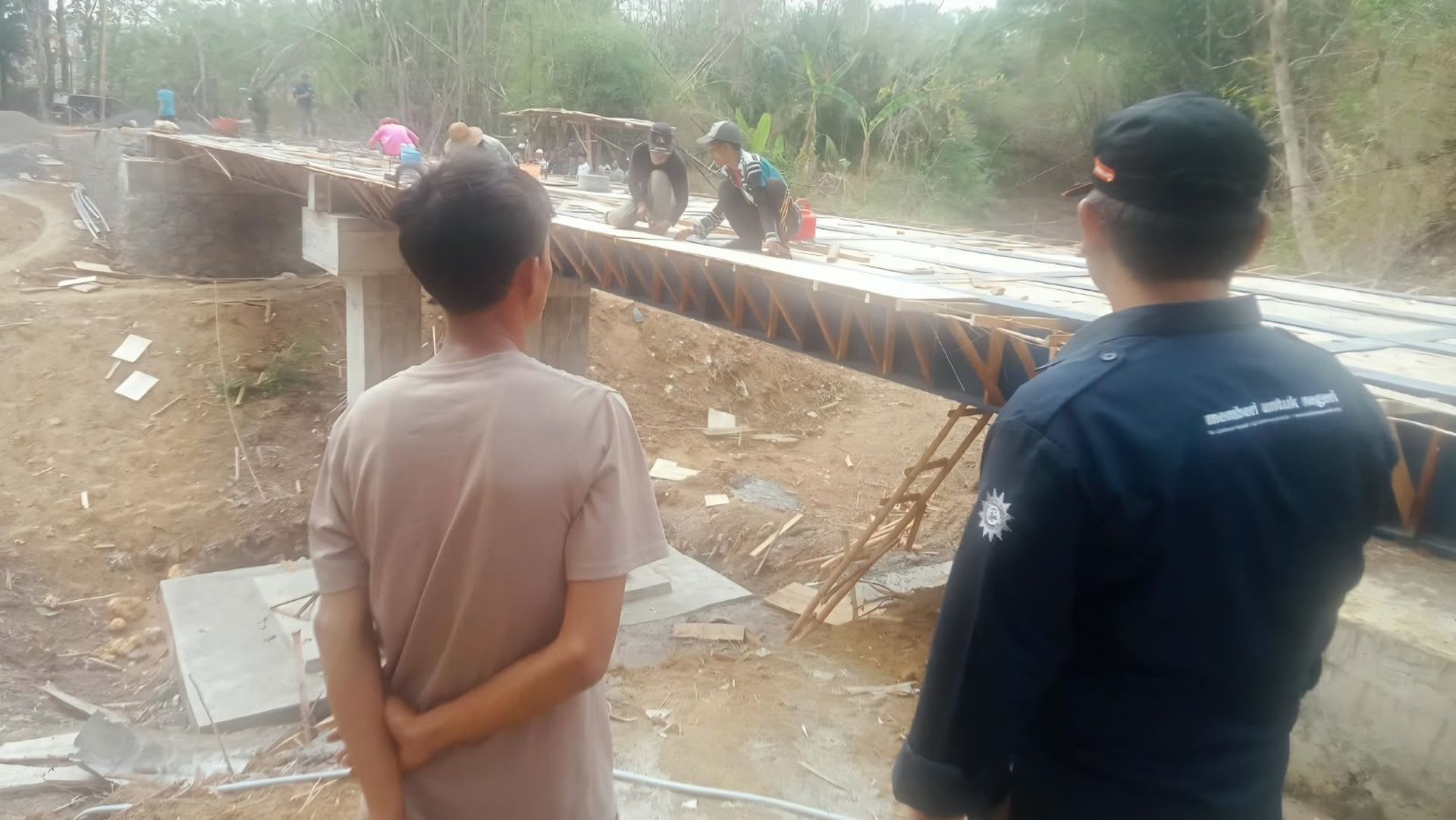 Pekerja membangun Jembatan Sirotol Mustaqim di Karang Penang, Kabupaten Sampang, dengan struktur penyangga dan landasan jembatan.